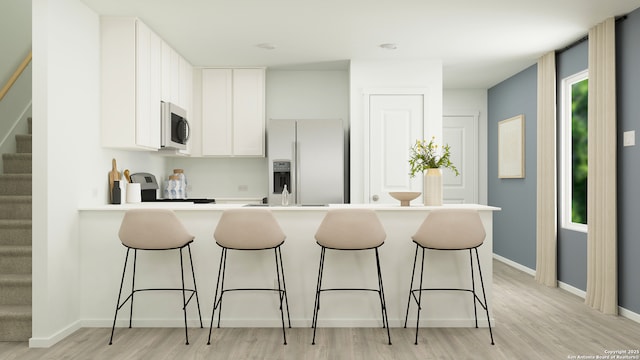 5658 Azure Aly, San Antonio, TX 78223 - kitchen featuring appliances with stainless steel finishes, light wood finished floors, a peninsula, and a breakfast bar area