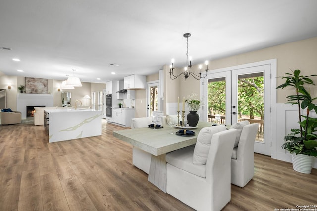 29302 Grand Coteau, Boerne, TX 78015 - dining space featuring a chandelier, light wood finished floors, a fireplace, wainscoting, and recessed lighting