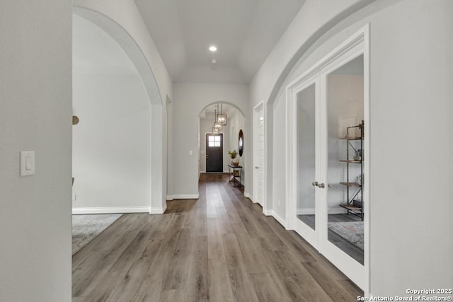 562 Orchard Way, New Braunfels, TX 78132 - hall featuring arched walkways, french doors, wood finished floors, vaulted ceiling, and a chandelier