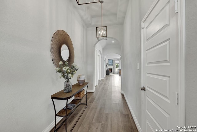 562 Orchard Way, New Braunfels, TX 78132 - hallway with arched walkways, wood finished floors, baseboards, and a chandelier
