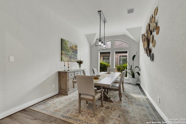 562 Orchard Way, New Braunfels, TX 78132 - dining space with baseboards, light wood-style floors, vaulted ceiling, a textured wall, and a chandelier
