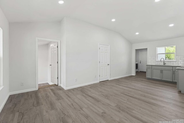 1711 Hermine, San Antonio, TX 78201 - unfurnished living room featuring vaulted ceiling, recessed lighting, light wood-style flooring, baseboards, and a sink
