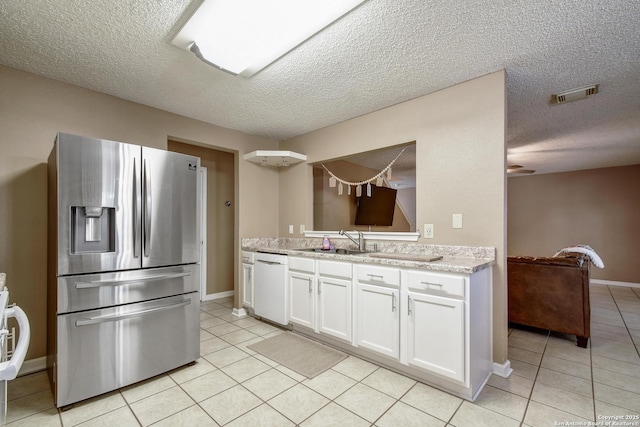 9311 Bowen Dr, San Antonio, TX 78250 - kitchen with stainless steel fridge, dishwasher, light tile patterned floors, a textured ceiling, and white cabinetry
