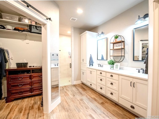 113 Bayberry Ct, La Vernia, TX 78121 - bathroom with double vanity, a stall shower, a walk in closet, wood finished floors, and recessed lighting
