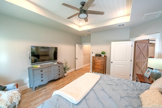 113 Bayberry Ct, La Vernia, TX 78121 - bedroom with a raised ceiling, light wood finished floors, a barn door, baseboards, and a ceiling fan