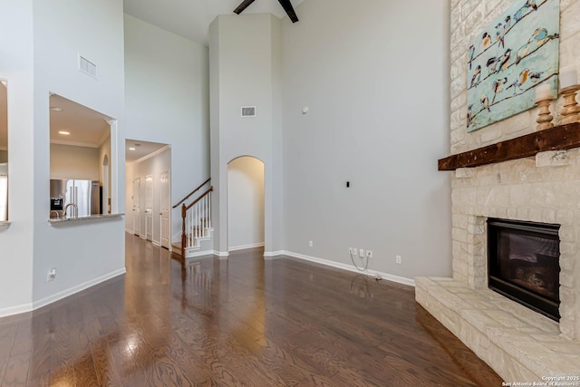 3319 Brooktree Ct, San Antonio, TX 78261 - unfurnished living room with a stone fireplace, a high ceiling, wood finished floors, baseboards, and stairway