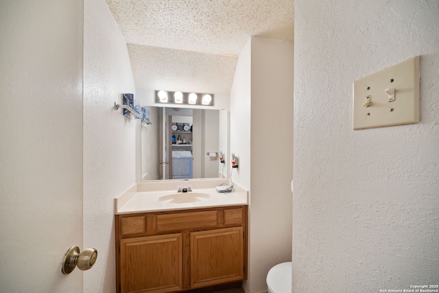 11334 Bald Mountain Dr, San Antonio, TX 78245 - bathroom featuring toilet, vanity, washer / dryer, a textured wall, and a textured ceiling
