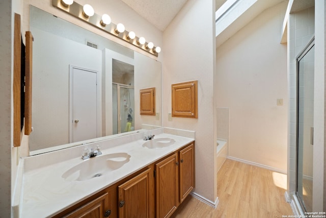 11334 Bald Mountain Dr, San Antonio, TX 78245 - full bath featuring wood finished floors, a shower stall, double vanity, a garden tub, and baseboards