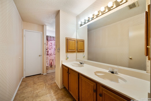 11334 Bald Mountain Dr, San Antonio, TX 78245 - full bathroom with wallpapered walls, baseboards, double vanity, and a textured ceiling