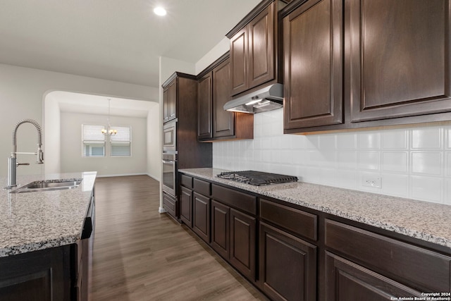 6595 Mason Vly, Schertz, TX 78108 - kitchen with under cabinet range hood, a sink, stainless steel appliances, a chandelier, and wood finished floors