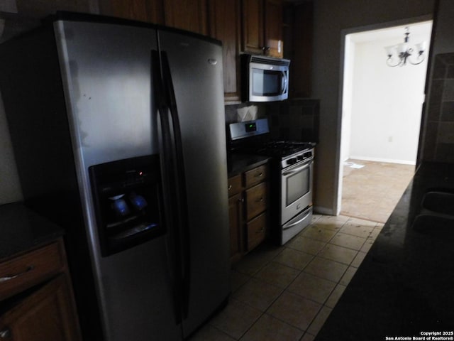 10223 Flatland Trl, Converse, TX 78109 - kitchen with stainless steel appliances, dark countertops, backsplash, dark tile patterned flooring, and a chandelier