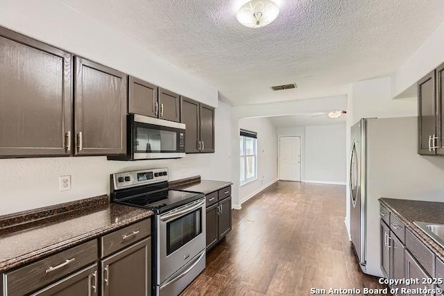 6862 Maple Spgs Unit 6862, San Antonio, TX 78249 - kitchen with appliances with stainless steel finishes, dark wood-style flooring, a textured ceiling, dark brown cabinetry, and baseboards