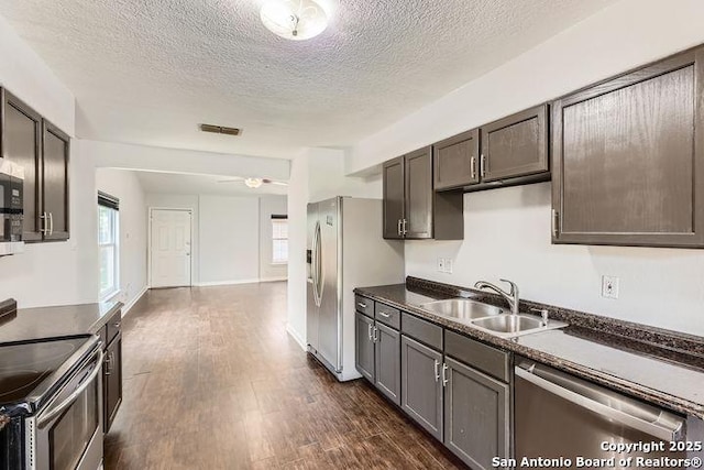6862 Maple Spgs Unit 6862, San Antonio, TX 78249 - kitchen with appliances with stainless steel finishes, a sink, dark countertops, a textured ceiling, and dark wood-style floors
