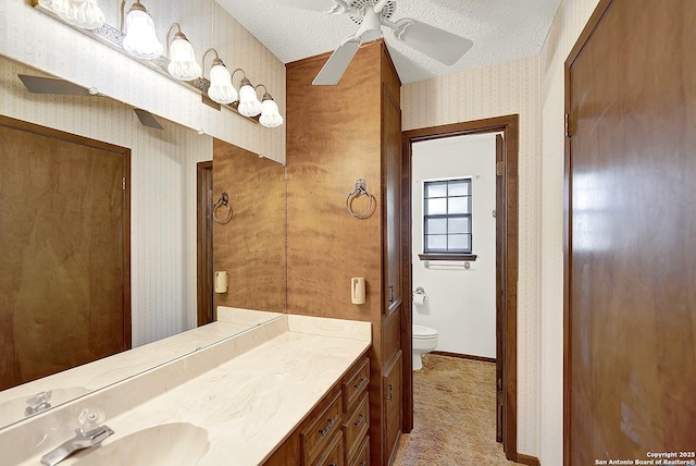 1212 County Road 337, La Vernia, TX 78121 - bathroom featuring wallpapered walls, toilet, vanity, a ceiling fan, and baseboards
