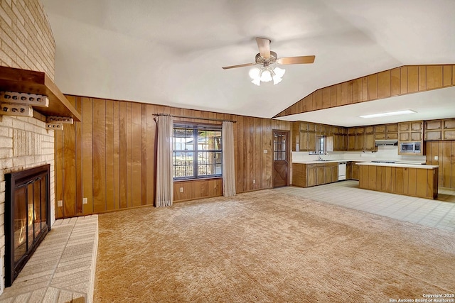 1212 County Road 337, La Vernia, TX 78121 - unfurnished living room featuring lofted ceiling, wood walls, a ceiling fan, a fireplace, and light colored carpet