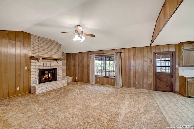 1212 County Road 337, La Vernia, TX 78121 - unfurnished living room featuring lofted ceiling, a ceiling fan, wood walls, healthy amount of natural light, and a brick fireplace