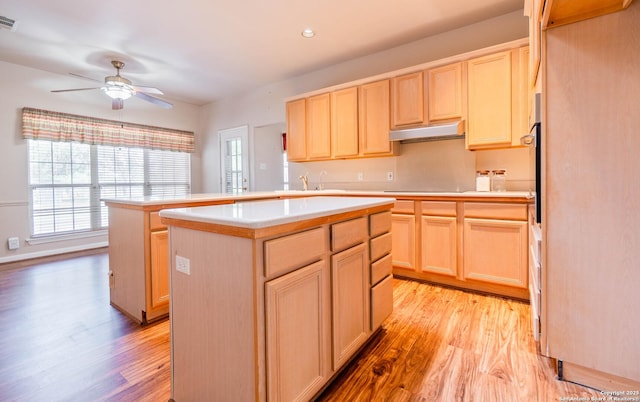 5535 Circle Oak Dr, Bulverde, TX 78163 - kitchen with under cabinet range hood, light wood-style flooring, a kitchen island, light countertops, and light brown cabinetry