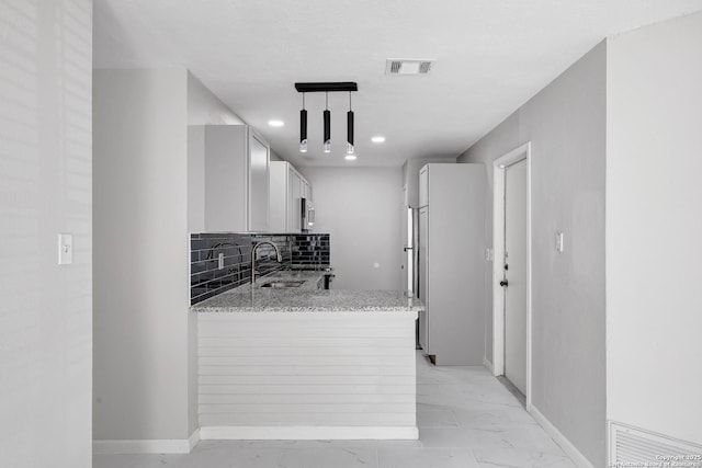 7311 Lansbury Dr, San Antonio, TX 78250 - kitchen with a sink, light stone counters, light marble finish floors, tasteful backsplash, and a peninsula