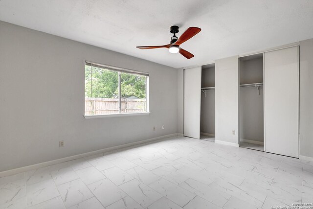 7311 Lansbury Dr, San Antonio, TX 78250 - unfurnished bedroom with multiple closets, light marble finish floors, baseboards, and a ceiling fan