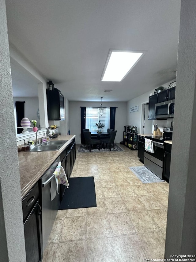 510 Tres Caminos, San Antonio, TX 78245 - kitchen featuring stainless steel appliances, a sink, dark cabinets, and a chandelier