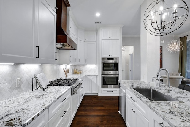11 Gemsbuck Rise, San Antonio, TX 78258 - kitchen with a sink, stainless steel appliances, a chandelier, wall chimney range hood, and dark wood finished floors