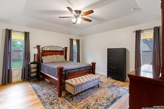 305 Rockmoor Dr, Georgetown, TX 78628 - bedroom featuring light wood-style floors, baseboards, a tray ceiling, and a ceiling fan