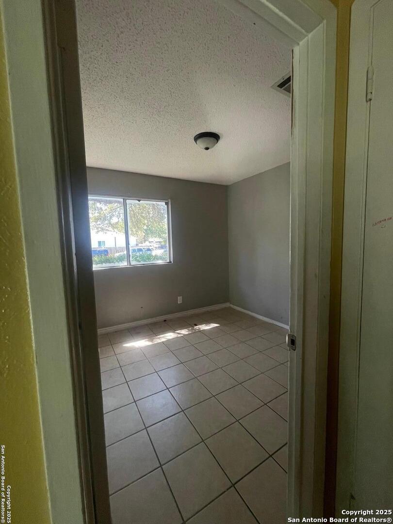 4402 Dove Spgs, Austin, TX 78744 - empty room with baseboards, tile patterned floors, and a textured ceiling