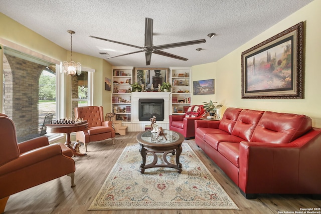 102 Southgate, Pleasanton, TX 78064 - living area with a textured ceiling, a ceiling fan, wood finished floors, a glass covered fireplace, and a chandelier
