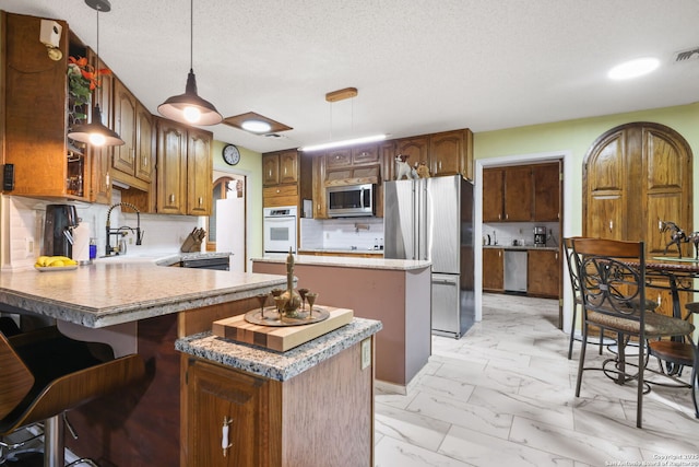 102 Southgate, Pleasanton, TX 78064 - kitchen featuring stainless steel appliances, a sink, light marble finish flooring, a peninsula, and decorative backsplash
