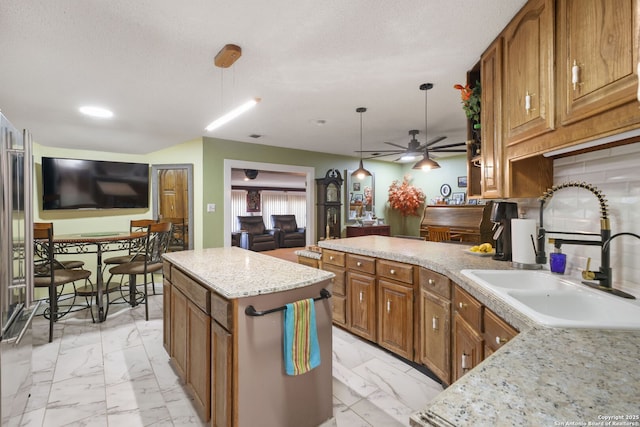 102 Southgate, Pleasanton, TX 78064 - kitchen with a sink, light marble finish flooring, brown cabinetry, a ceiling fan, and pendant lighting