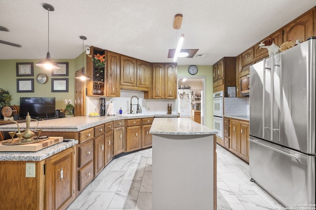 102 Southgate, Pleasanton, TX 78064 - kitchen featuring freestanding refrigerator, light marble finish floors, double oven, a kitchen island, and a textured ceiling