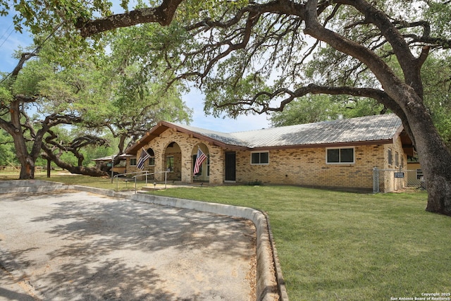 102 Southgate, Pleasanton, TX 78064 - view of front of property featuring brick siding, a front yard, and metal roof