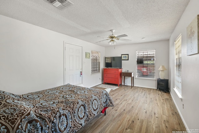 102 Southgate, Pleasanton, TX 78064 - bedroom featuring wood finished floors, multiple windows, baseboards, a textured ceiling, and a ceiling fan