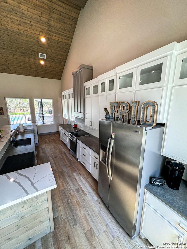 34 Lazy Day, Concan, TX 78838 - kitchen with high vaulted ceiling, stainless steel appliances, a sink, white cabinets, and wood finished floors