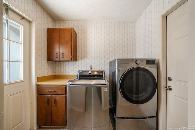 2102 Oak Wild St, San Antonio, TX 78232 - laundry area with wallpapered walls, washer and dryer, cabinet space, a textured ceiling, and tile patterned floors
