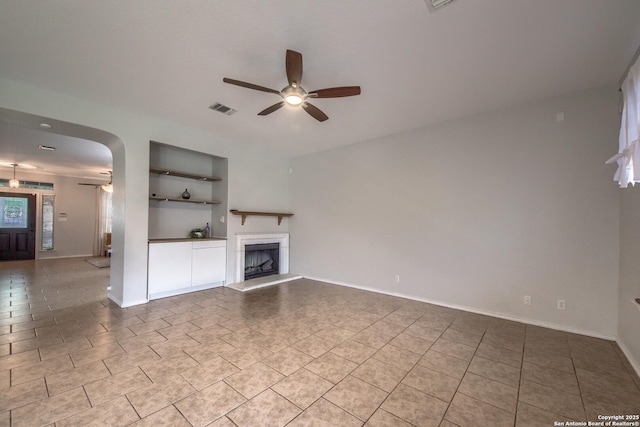 112 Springtree Bnd, Cibolo, TX 78108 - unfurnished living room with ceiling fan, built in features, arched walkways, and tile patterned floors