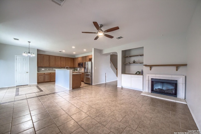 112 Springtree Bnd, Cibolo, TX 78108 - unfurnished living room with built in features, a ceiling fan, a fireplace with raised hearth, baseboards, and a chandelier