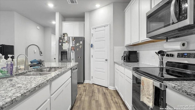 229 Colebrook Way, Cibolo, TX 78108 - kitchen with appliances with stainless steel finishes, a sink, white cabinets, light wood-style flooring, and tasteful backsplash