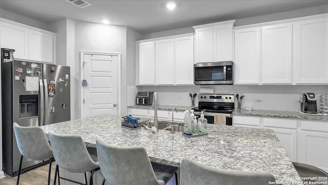 229 Colebrook Way, Cibolo, TX 78108 - kitchen with stainless steel appliances, white cabinetry, light stone counters, a breakfast bar, and recessed lighting
