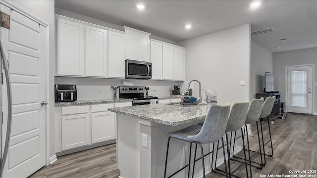 229 Colebrook Way, Cibolo, TX 78108 - kitchen with appliances with stainless steel finishes, light wood-type flooring, a sink, a kitchen breakfast bar, and white cabinets