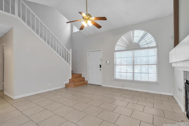 10222 Canton Fld, San Antonio, TX 78245 - unfurnished living room with ceiling fan, stairway, a fireplace, light tile patterned floors, and high vaulted ceiling