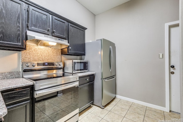 9331 Autumn Sunrise, San Antonio, TX 78254 - kitchen with appliances with stainless steel finishes, under cabinet range hood, light tile patterned floors, dark cabinets, and baseboards