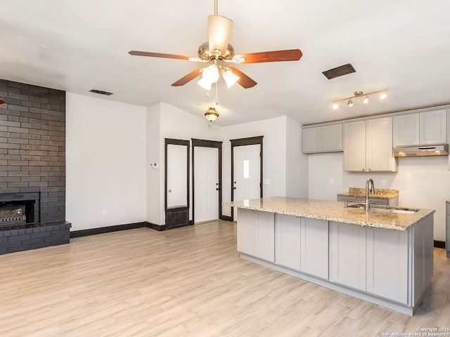 3601 Candleridge, San Antonio, TX 78244 - kitchen with a sink, a ceiling fan, under cabinet range hood, light stone countertops, and light wood-style flooring