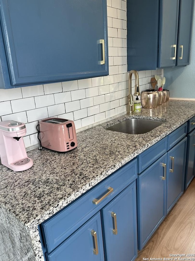 2007 S Presa, San Antonio, TX 78210 - kitchen featuring blue cabinets, a sink, backsplash, and light stone counters