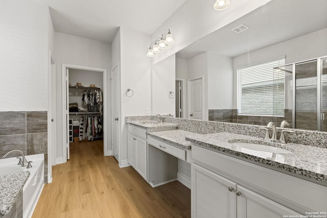7618 Desperado, Boerne, TX 78015 - bathroom featuring wood finished floors, double vanity, a bath, a shower stall, and a spacious closet