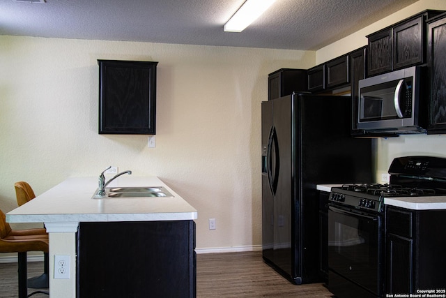 5922 Autumn Palms, San Antonio, TX 78242 - kitchen featuring black gas stove, stainless steel microwave, a sink, dark cabinetry, and a textured ceiling