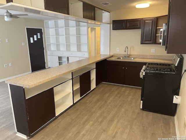 1538 Thorain, San Antonio, TX 78201 - kitchen with black gas range, a sink, a peninsula, and dark brown cabinetry