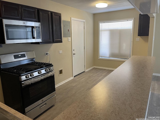 1538 Thorain, San Antonio, TX 78201 - kitchen with stainless steel appliances, dark cabinets, electric panel, baseboards, and wood finished floors