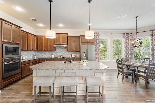 25318 Pleasant Bch, San Antonio, TX 78255 - kitchen with appliances with stainless steel finishes, crown molding, brown cabinetry, backsplash, and a kitchen bar