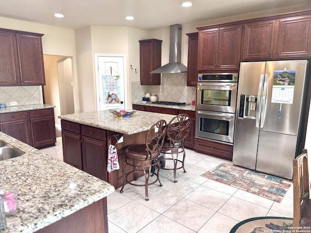 187 Tracks Trl, Center Point, TX 78010 - kitchen with stainless steel appliances, wall chimney range hood, decorative backsplash, arched walkways, and light stone counters